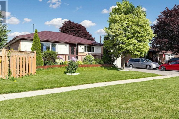 Front view of a beige and cream bungalow with a dark brown roof and mature trees. - 487 Wilson Road S, Oshawa
