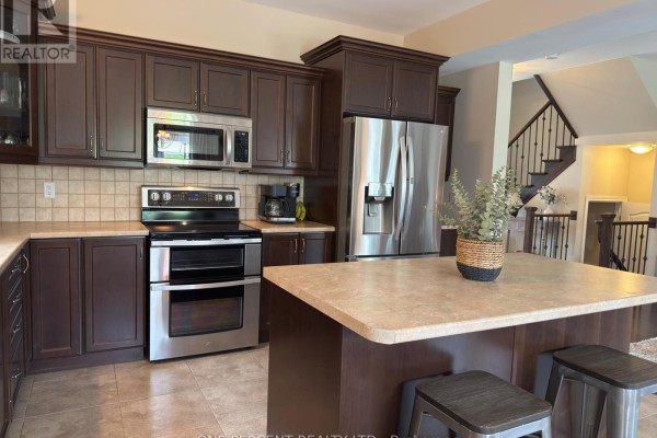 Kitchen featuring dark wood cabinets, stainless steel appliances, and a view of the staircase. - 4871 Northgate Crescent, Lincoln