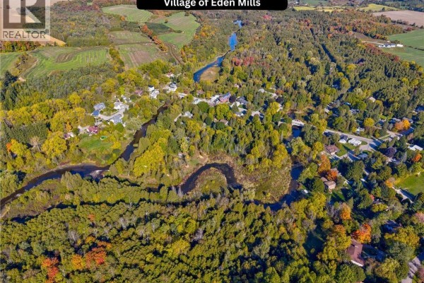 Aerial view of the village of Eden Mills, showcasing a winding river surrounded by trees and houses. - 4875 Wellington Rd 29, Eden Mills