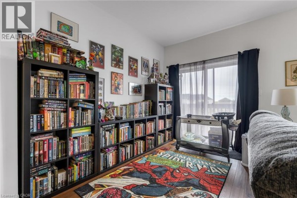 Den area with floor-to-ceiling bookshelves, a Spider-Man themed rug, and a baby playpen. - 4879 Connor Drive, Beamsville