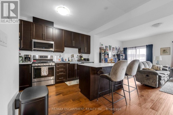 Kitchen with dark wood cabinets, stainless steel appliances, and island seating. - 4879 Connor Drive, Lincoln