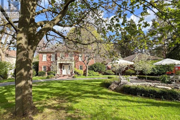 View of the house from the side yard, featuring a large tree in the foreground. - 488 Macdonald Road, Oakville