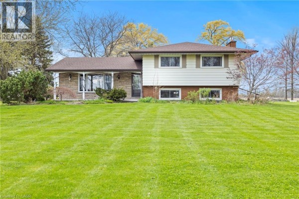 Front view of a split-level house with stone and vinyl siding, a covered porch, and a bright blue sky. - 488 Townline Road, Niagara On The Lake
