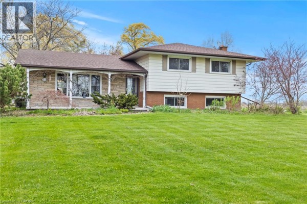 Close-up of the front entrance of a house featuring a stone facade and a covered porch with columns. - 488 Townline Road, Niagara On The Lake