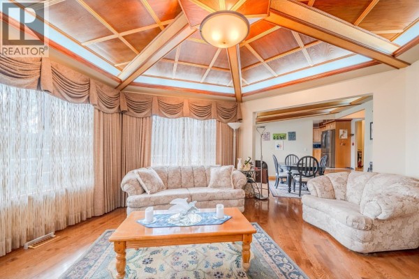 Living room with two floral sofas, a wooden coffee table, and a large wood-paneled ceiling with a skylight. - 4882 Gloinnzun Crescent, 108 Mile Ranch