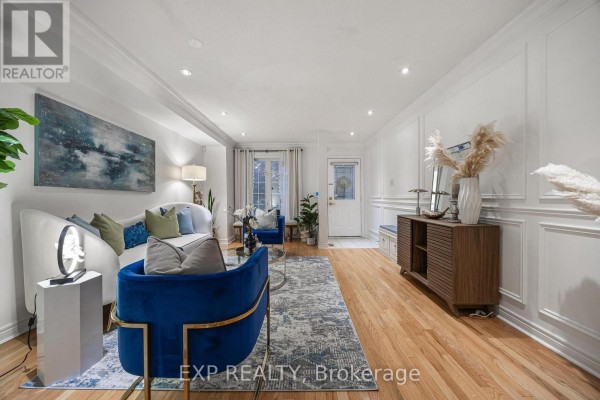 Living room with white walls, ornate molding, hardwood floors, a white sofa, and blue accent chairs. - 4882 Vienna Court, Mississauga