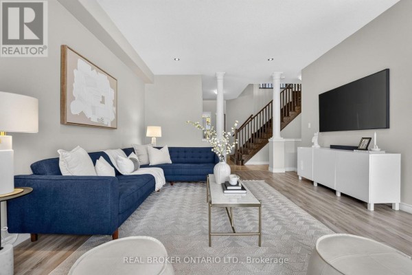 Living room with a navy blue sectional sofa, white coffee table, fireplace, and wood staircase. - 4890 Allan Court, Lincoln