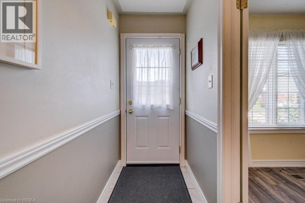 Interior hallway with a white door at the end, beige walls, and wainscoting. - 48c Harris Avenue, Brantford