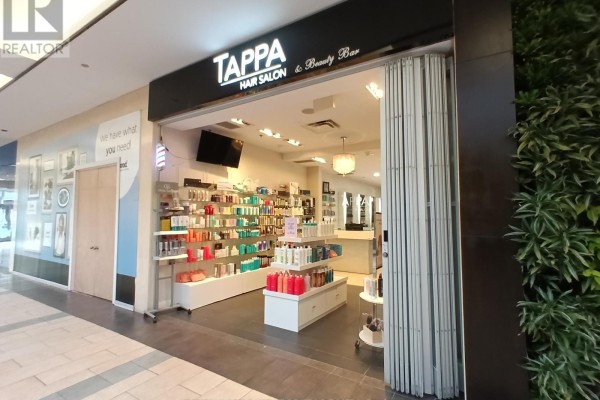 Exterior view of Tappa Hair Salon entrance with products displayed on shelves to the left and a green living wall on the right. - 49 - 2121 Carling Avenue, Ottawa