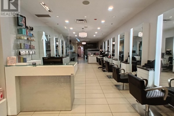 Interior view of Tappa Hair Salon showing a white reception desk with a glass partition and rows of styling stations. - 49 - 2121 Carling Avenue, Ottawa