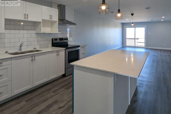 Modern white kitchen with quartz island, stainless steel appliances, and subway tile backsplash. - 49 - 55 Adam Street, The Nation