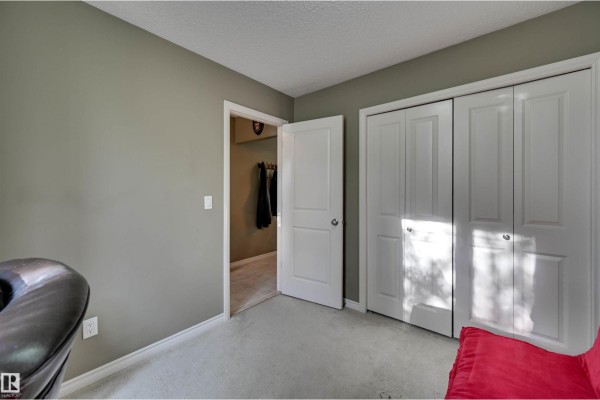 Bedroom with light grey carpet, closed white closets, and doorway to hallway. - #49 10 Woodcrest Ln, Fort Saskatchewan
