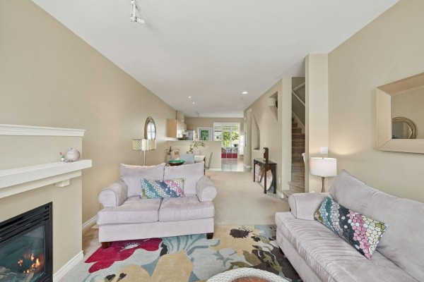 Living room and dining area with two sofas, fireplace, and view of the kitchen and stairs. - 49 18828 69 Avenue, Surrey