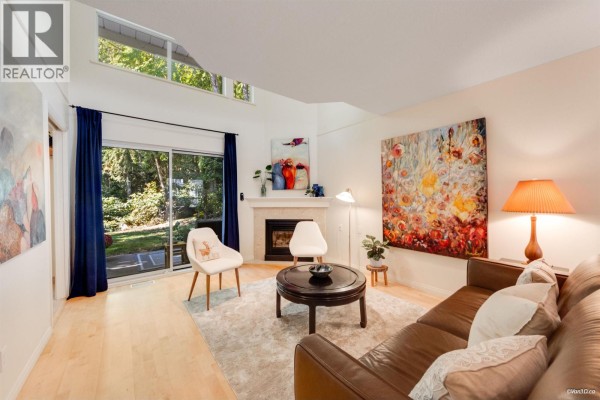 Living room with a fireplace, leather sofa, round coffee table, and artwork. - 49 650 Roche Point Drive, North Vancouver
