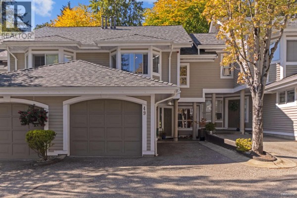 Exterior of a townhouse complex with attached garages and beige siding. - 49 650 Roche Point Drive, North Vancouver