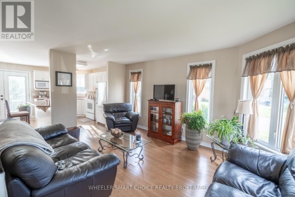 Living room with leather sofas and hardwood floors, opening to kitchen - 49 Barnhart Drive South Stormont