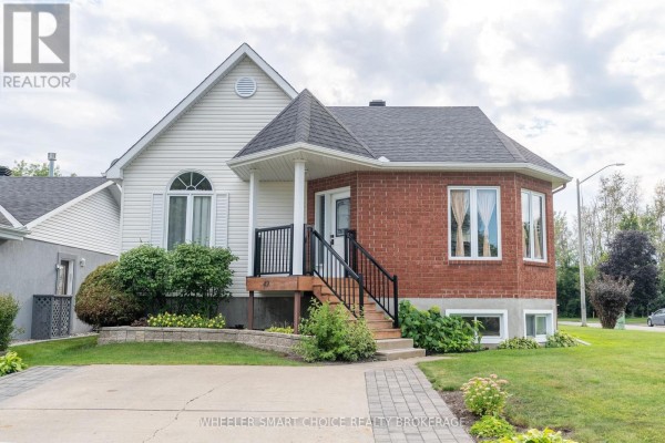 Red brick house with white siding, covered porch, and green landscaping. - 49 Barnhart Drive, South Stormont