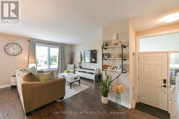 Living room with a sofa, coffee table, television, and a large window. - 49 Bond Street, Orillia