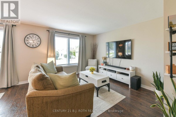 Living room with a sectional sofa, a large window, and wall-mounted television. - 49 Bond Street, Orillia
