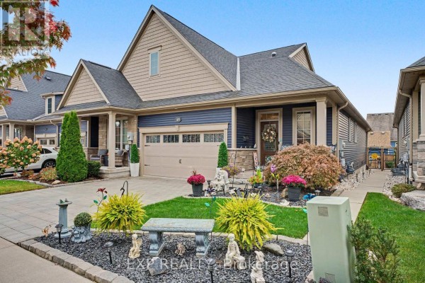 Front exterior of a townhouse with a garage, blue siding, stone accents, and a decorative front lawn. - 49 Campbell Street, Thorold
