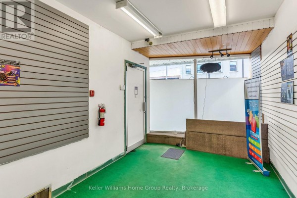 Interior of a commercial space with green carpet, slatted walls, a fire extinguisher, and a glass door. - 49 Cork Street E, Guelph