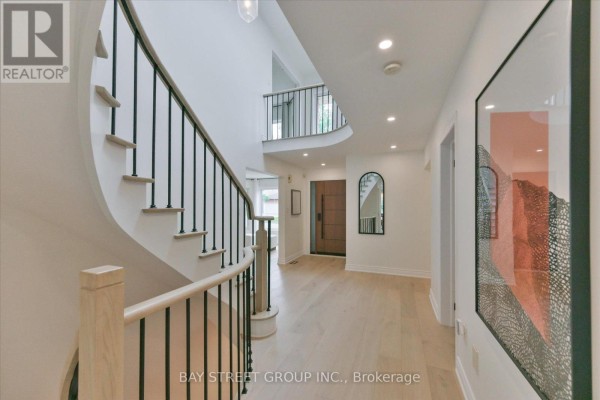 View from entryway looking towards front door and staircase, with modern art on wall. - 49 Cygnus Drive, Richmond Hill