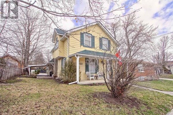 Right side exterior view of the yellow house with a lawn and trees. - 49 John Street E, Bradford West Gwillimbury