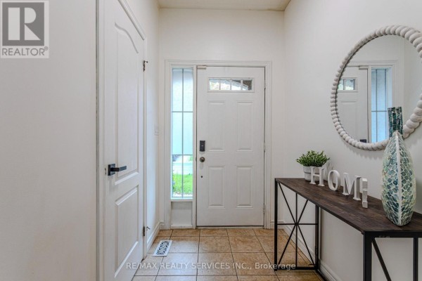 Interior entryway with tiled floor, white walls, a console table with decor, and a round mirror. - 49 Marina Point Crescent N, Hamilton