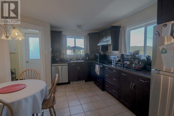 Kitchen with dark brown cabinets, stainless steel appliances, and a round dining table. - 49 Maxwell Place, St  John S