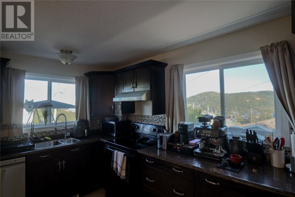 Kitchen with dark brown cabinets, granite countertops, and large windows overlooking a valley. - 49 Maxwell Place, St  John S