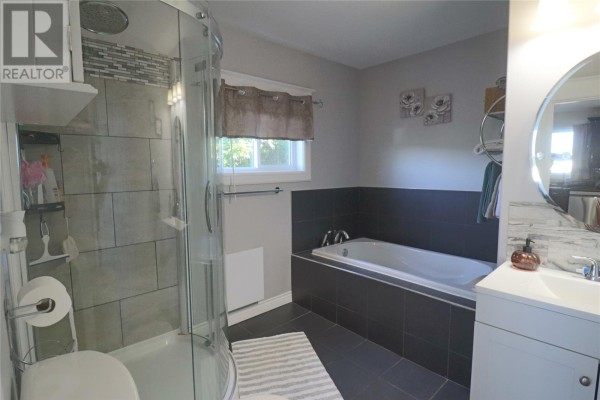 Bathroom with a separate shower stall, a large corner bathtub, and a white vanity. - 49 Maxwell Place, St  John S