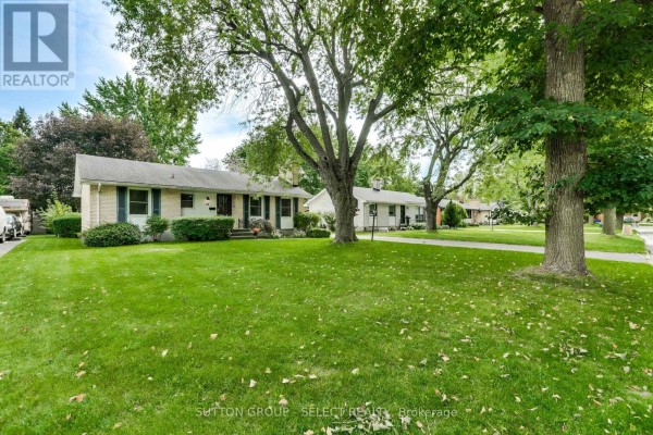 Street view of the house with mature trees and green lawns. - 49 Mcleod Crescent, London North