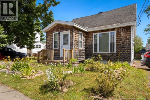 View of the house from the front yard with flower beds and a driveway. - 49 Mcsweeney Avenue, Moncton