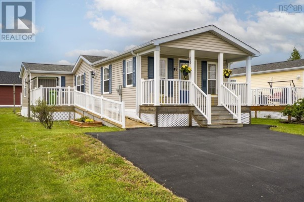 Side exterior view of a beige mobile home with a covered porch and ramp. - 49 Merriweather Crescent, Garlands Crossing