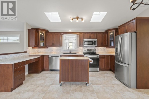 Interior view of a spacious kitchen with dark wood cabinets and stainless steel appliances. - 49 Merriweather Crescent, Garlands Crossing