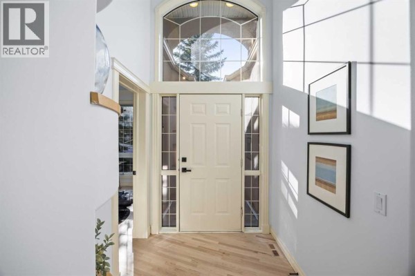 Home office with a glass desk, blue chair, black rug, and large window. - 49 Patina Terrace Sw, Calgary