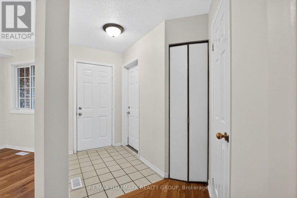 Interior entrance hallway with tiled floor, white doors, and bi-fold closet. - 49 Robarts Crescent, Ottawa
