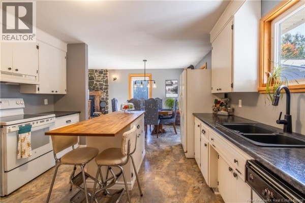 View of the kitchen, dining area, and stone fireplace in the open-concept living space. - 49 Yeomans Road, Mill Brook