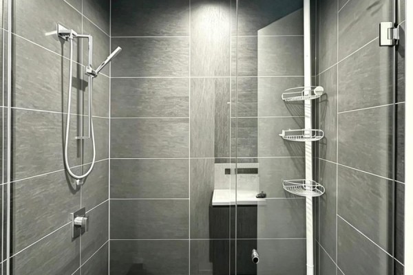 Walk-in shower with grey tile, chrome showerhead, and glass door. - 4901 - 101 Charles Street E, Toronto