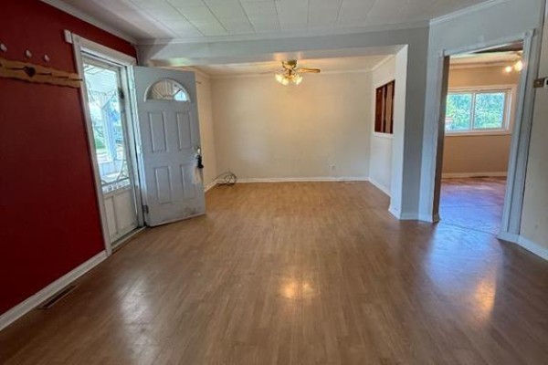 View from entryway showing living room with wood laminate floors and red accent wall. - 4904 58th Avenue, High Prairie