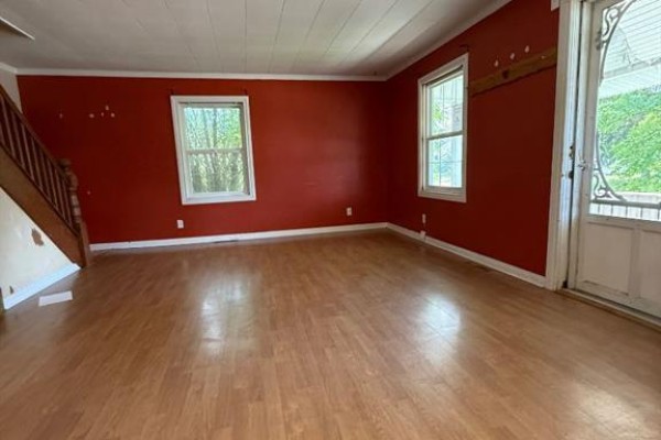 Living room with wood laminate floors, a red accent wall, and two windows. - 4904 58th Avenue, High Prairie