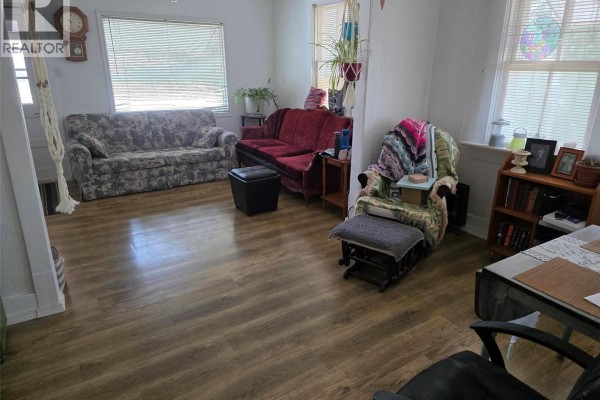 Living room with wood laminate flooring, floral sofas, a recliner, and a bookshelf. - 4904 Tribune Street, Macklin