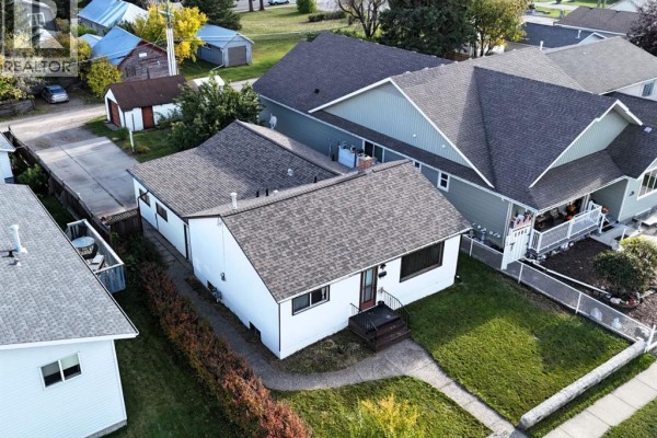 Aerial view of the property showing the white house, driveway, and surrounding neighboring houses. - 4907 7 Avenue, Edson
