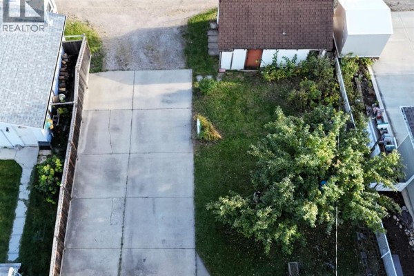 Top-down view of a concrete driveway with a small detached building and surrounding grass. - 4907 7 Avenue, Edson
