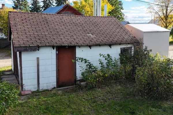 Exterior view of a detached white building with a brown door and a brown asphalt shingled roof. - 4907 7 Avenue, Edson