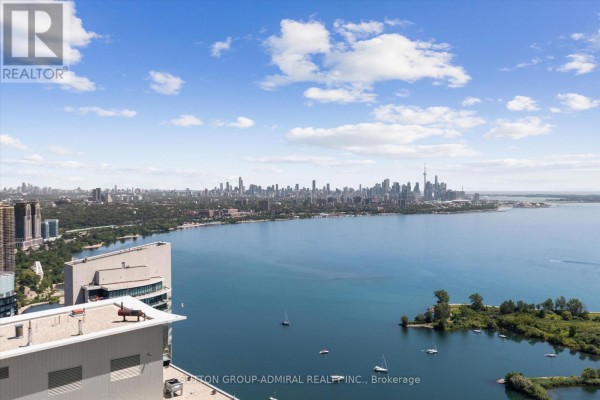 Panoramic view of a large city skyline across a wide blue bay with sailboats and islands. - 4908 - 30 Shore Breeze Drive, Toronto