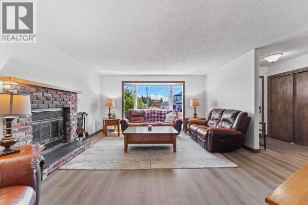 Living room with a red brick fireplace, bay window, leather sofas, and a large area rug. - 4908 56 Street W, Forestburg