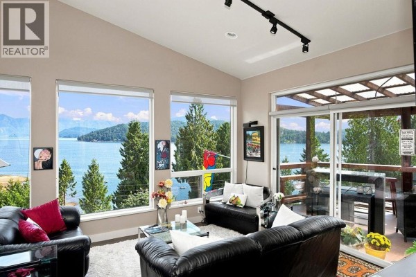 Living room seating area with large windows offering panoramic views of water and mountains. - 491 Woodland Avenue, Gibsons