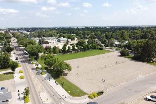 Aerial view of a residential area with an empty paved lot in the center. - 4911 55a St, Wetaskiwin