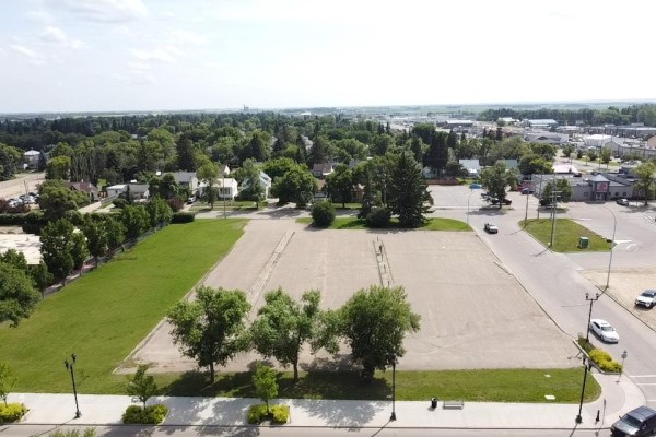 Aerial view of a town with an open, paved lot and surrounding residential buildings. - 4911 55a St, Wetaskiwin